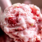 Delicious homemade frozen yogurt topped with fresh strawberries and mint leaves.