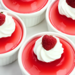 Colorful Greek Yogurt Jello Cups garnished with fresh fruits and mint leaves on a bright table.