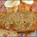 Freshly sliced banana bread on a cutting board with chocolate chips and ripe bananas.