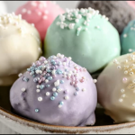 Colorful Oreo truffles with almond bark drizzle and sprinkles on a decorative plate.
