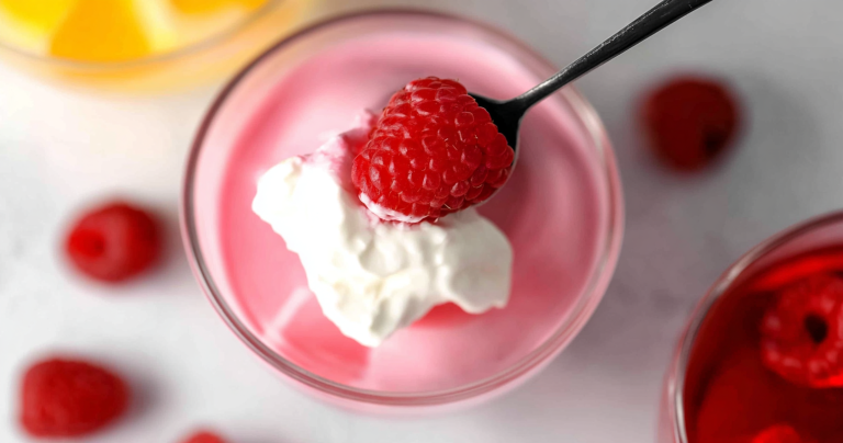 Delicious Greek yogurt jello served in a bowl with fresh berries and whipped cream on top.