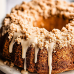 Slice of Coffee Cake Bundt Cake with cinnamon swirl and brown butter glaze on a wooden table.