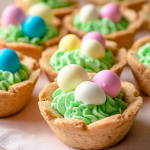 Easter Basket Sugar Cookie Cups filled with vanilla buttercream and topped with chocolate eggs on a festive table.