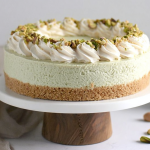 Slice of no bake pistachio cheesecake with whipped cream and chopped pistachios on a plate.
