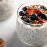 Creamy yogurt chia pudding served with fresh berries and nuts on a rustic wooden table.