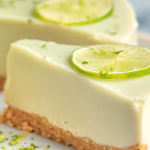 Slice of no bake lime cheesecake with whipped cream and lime zest on a wooden table