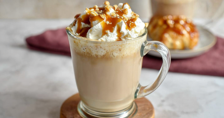Close-up of Dutch Bros Golden Eagle coffee drink with whipped cream and caramel, styled with coffee beans.