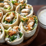 Delicious Chicken Caesar Wrap filled with lightly breaded chicken, romaine lettuce, and parmesan, cut in half on a wooden table.