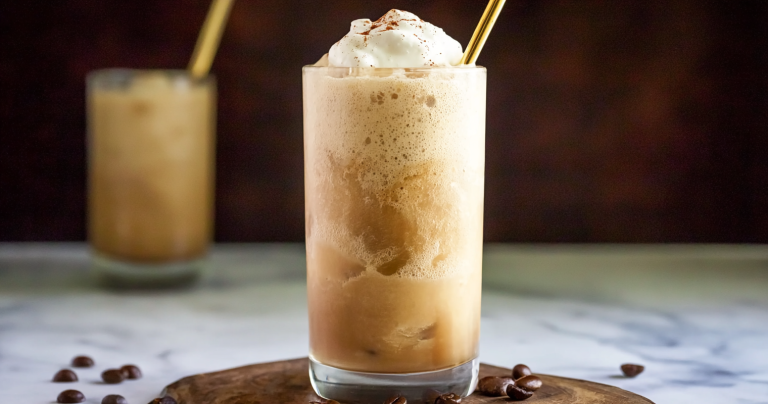 Refreshing frozen Coffee Slush topped with whipped cream in a glass on a wooden table.
