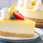 Slice of no-bake jello cheesecake topped with berries and whipped cream on a decorative plate.