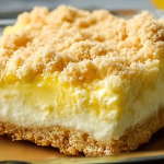 A slice of Lemon Cream Cheese Dump Cake topped with whipped cream and lemon zest on a white plate.