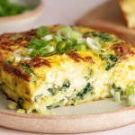 Delicious cottage cheese egg bake served in a rustic dish, garnished with fresh spinach and Parmesan cheese, on a wooden table.