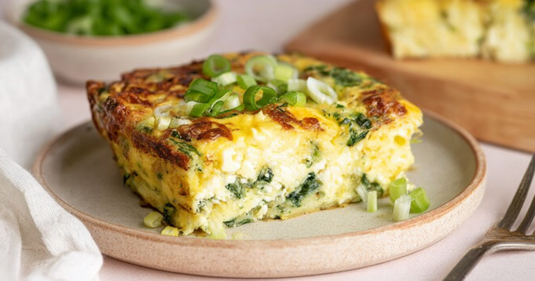 Delicious cottage cheese egg bake served in a rustic dish, garnished with fresh spinach and Parmesan cheese, on a wooden table.