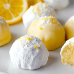 Delicious lemon truffles with powdered sugar on a plate, garnished with lemon slices and mint leaves.