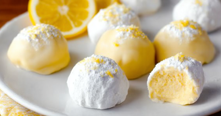 Delicious lemon truffles with powdered sugar on a plate, garnished with lemon slices and mint leaves.