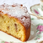 Slice of Irish tea cake adorned with fresh berries and whipped cream on a wooden table
