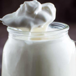 Creamy Greek yogurt icing drizzled on banana bread with banana slices and powdered sugar garnish