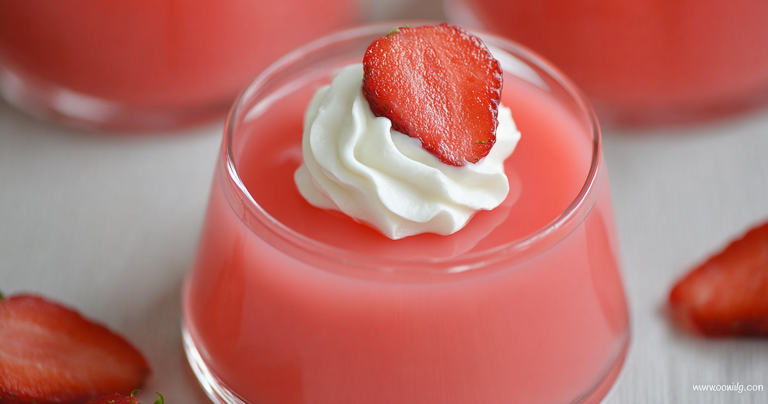 Bowl of Greek yogurt jello with whipped cream and strawberries on a wooden table