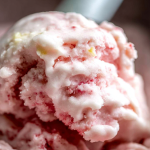 Bowl of creamy homemade frozen yogurt topped with fresh strawberries and banana slices, drizzled with honey.