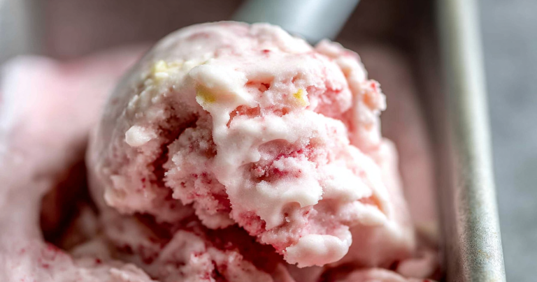 Bowl of creamy homemade frozen yogurt topped with fresh strawberries and banana slices, drizzled with honey.