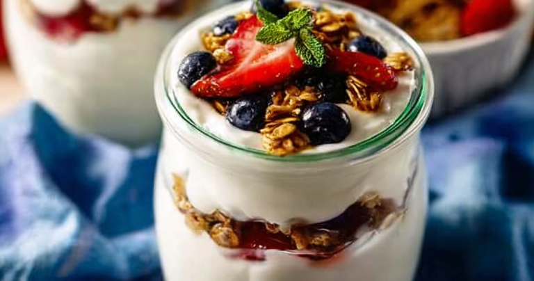 Close-up of a delicious Greek yogurt parfait layered with fresh berries and granola in a glass jar.