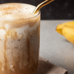 Delicious banana bread latte with whipped cream and cinnamon, served in a glass.