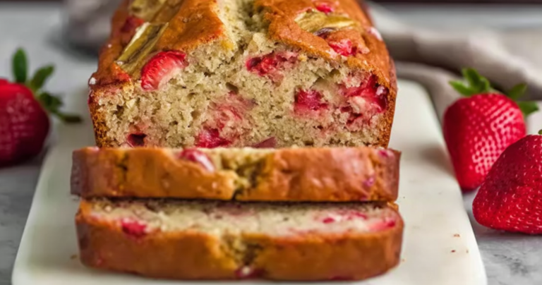 A delicious slice of strawberry banana bread garnished with fresh strawberries and banana slices on a white plate.