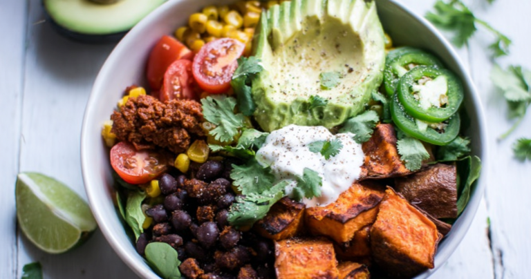 Colorful Sweet Potato Taco Bowl with tomatoes, avocado, and cilantro