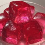 Dr Oz pink gelatin cubes garnished with lemon slices and cranberries on a colorful plate.