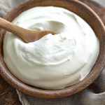 Bowl of homemade Greek yogurt topped with fresh fruits and nuts ready to eat.