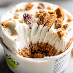 Delicious yogurt cheesecake slice topped with berries and honey on a wooden table.