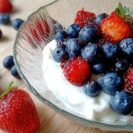 Greek yogurt topped with fresh blueberries and strawberries drizzled with honey