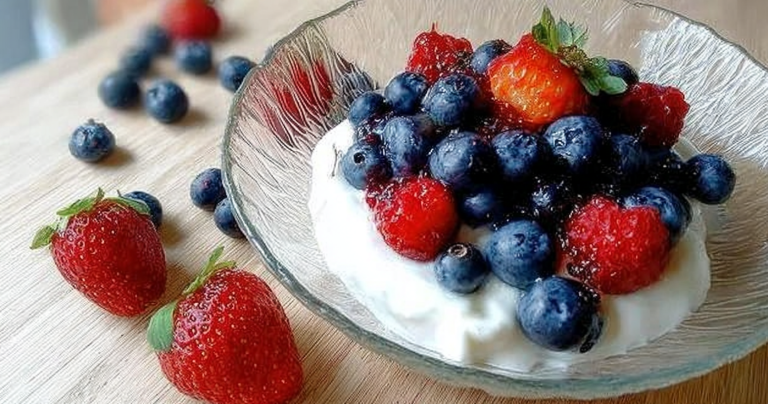 Greek yogurt topped with fresh blueberries and strawberries drizzled with honey
