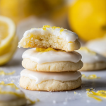 Freshly baked lemon meltaway cookies garnished with powdered sugar and lemon zest on a rustic wooden table.