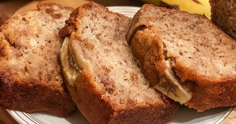 Sliced banana bread on a cutting board with ripe bananas in the background