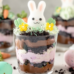 Easter Dirt Cups topped with colorful coconut, candy eggs, and Peeps in mason jars on a festive Easter background.