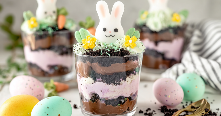 Easter Dirt Cups topped with colorful coconut, candy eggs, and Peeps in mason jars on a festive Easter background.