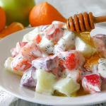 Colorful creamy yogurt fruit salad with fresh strawberries, blueberries, and sliced bananas, topped with honey.