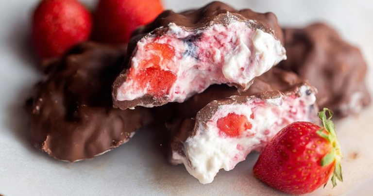 Frozen chocolate strawberry yogurt clusters on a plate with fresh strawberries.