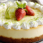 Slice of key lime cheesecake with whipped cream and lime garnish on a wooden table