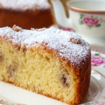 Slice of Irish tea cake with fresh berries and whipped cream on a floral plate.