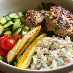 Mediterranean turkey burger bowl with roasted potatoes and hummus on a wooden table.