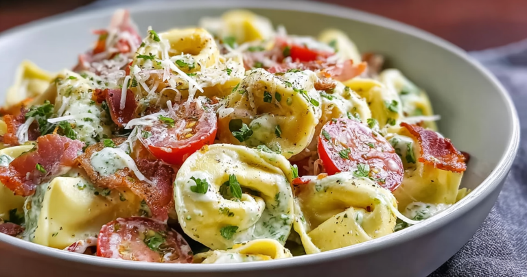 Bowl of fresh grinder tortellini salad with grape tomatoes and pepperoncini on a wooden table.