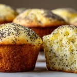 Freshly baked lemon poppy seed muffins on a white plate, adorned with lemon slices and a light lemon glaze.