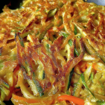 Delicious Korean vegetable pancakes served with soy dipping sauce, featuring vibrant colors from fresh vegetables.