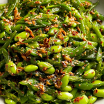 Chili crisp snap pea salad with snap peas, edamame, cilantro, and scallions in a rustic bowl.