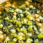 A bowl of vibrant spring minestrone soup with fresh vegetables, garnished with herbs.