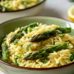 Delicious lemon orzo with asparagus, crumbled feta cheese, and fresh parsley in a bowl.