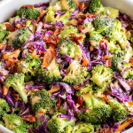 Crunchy broccoli salad with purple cabbage, bacon bits, and honey Dijon vinaigrette in a bright bowl.