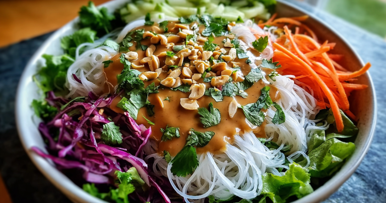 Colorful spring roll salad with crunchy vegetables and peanut dressing in a large bowl, garnished with roasted peanuts.
